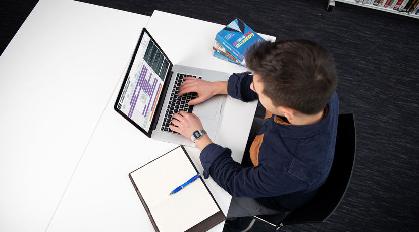 Student at a desk in the library with their laptop open, looking at Edinburgh College progression maps on the screen.