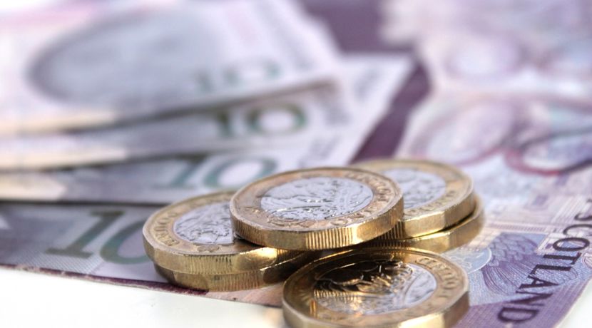 A stack of pound coins on top of bank notes.