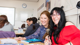 Two exchange students working together at a desk in a classroom.