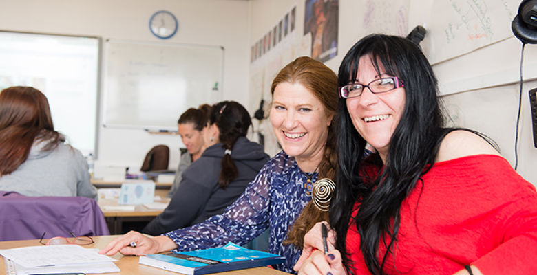 Two exchange students working together at a desk in a classroom.