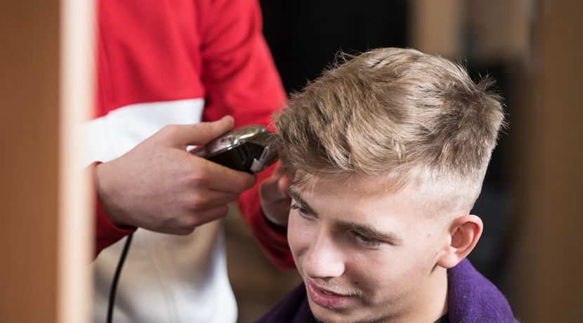 Barbering student clipping a client's hair in the salon.